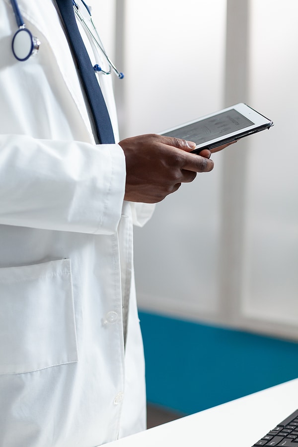 Close-up view of African American therapist doctor holding a tablet for patient consultation.