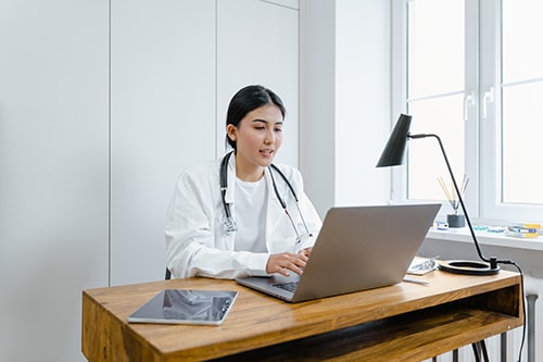 Doctor working at desk with computer to represent revenue cycle management services in Bloomington, MN